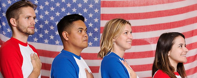 Team members hold their hands over their hands with an American flag draped in the background.